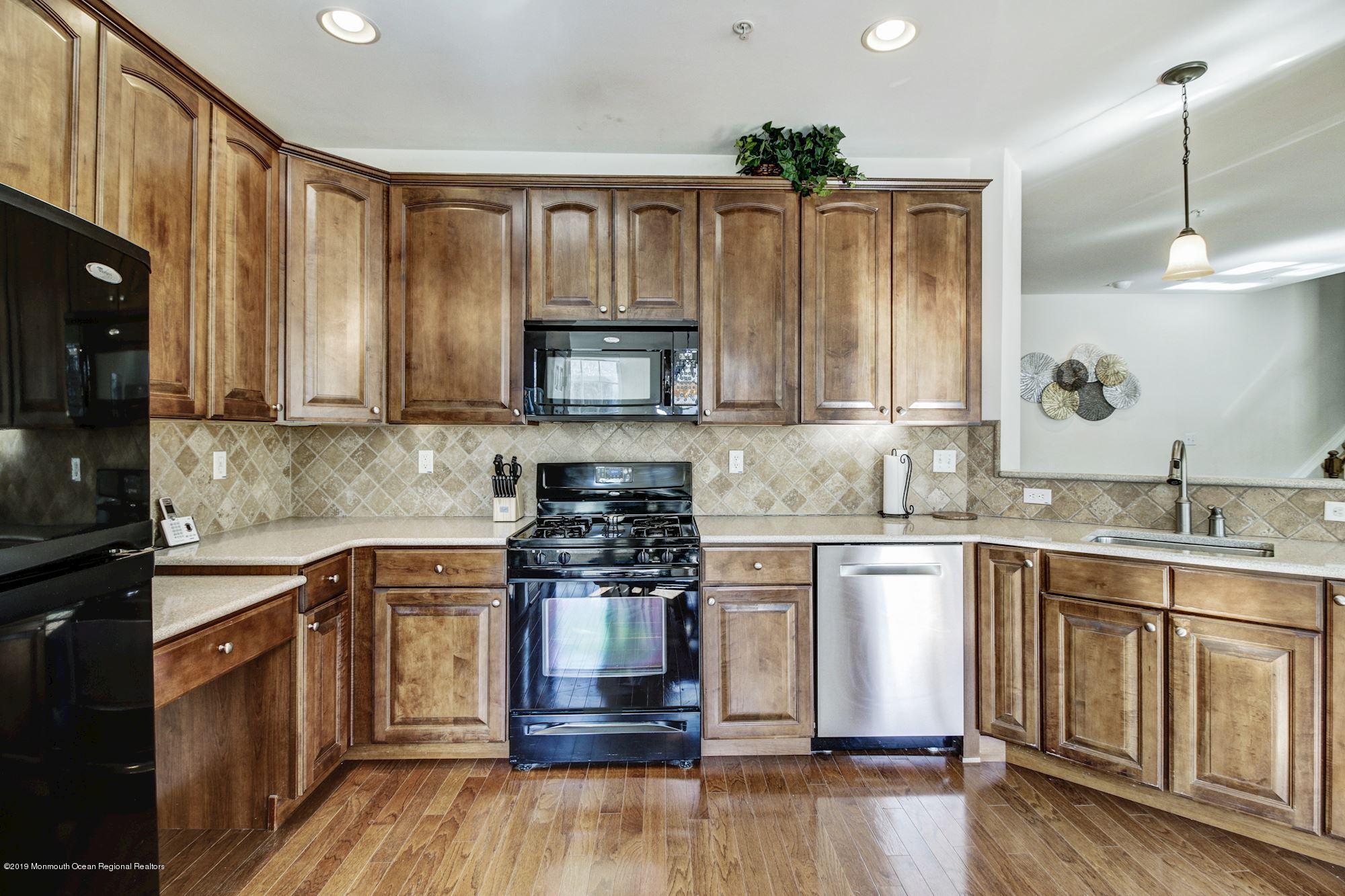 1006 Abby Road Middletown, NJ 07748 - Photo 19 of 44 a kitchen with stainless steel appliances granite countertop a stove a sink dishwasher and a microwave oven with wooden floor