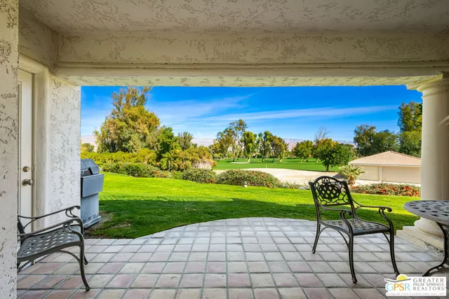 a view of a chairs and table in patio with a yard