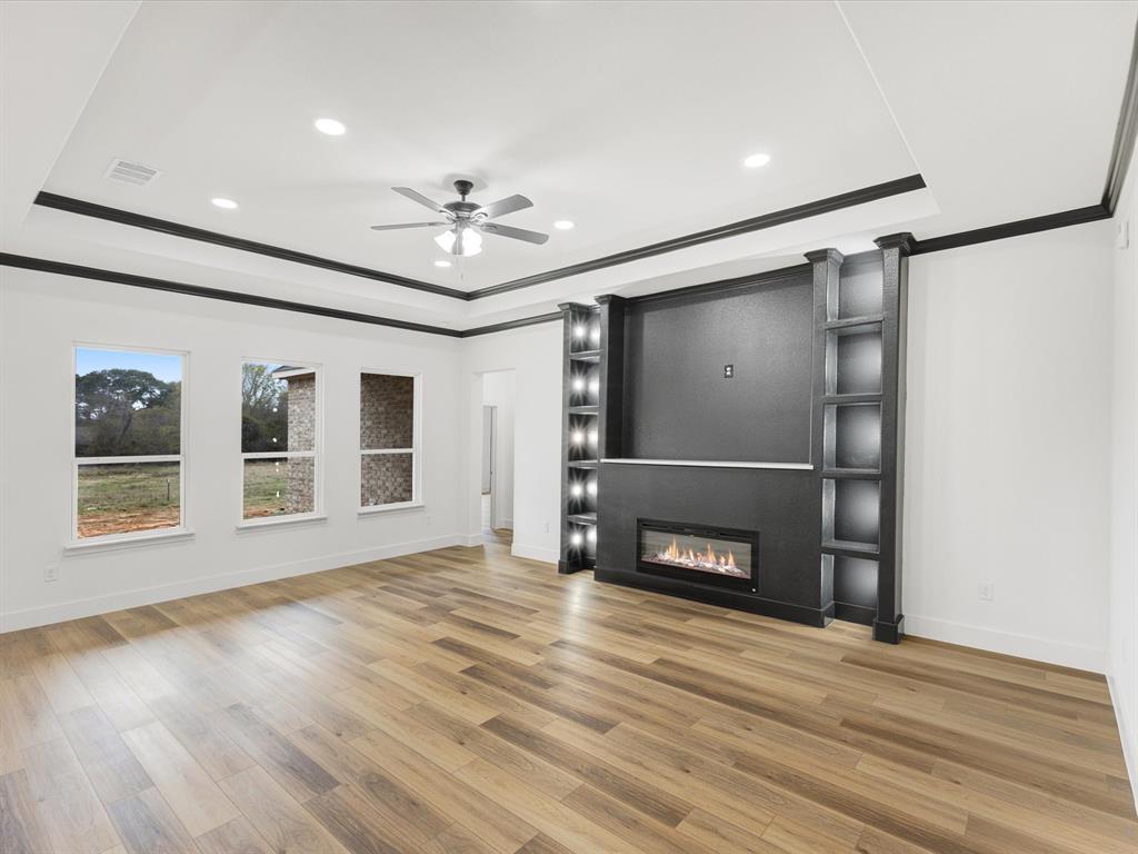 544 Shepherd Road Combine, TX 75159 - Photo 8 of 36 Unfurnished living room featuring ornamental molding, a raised ceiling, a fireplace, ceiling fan, and light wood finished floors