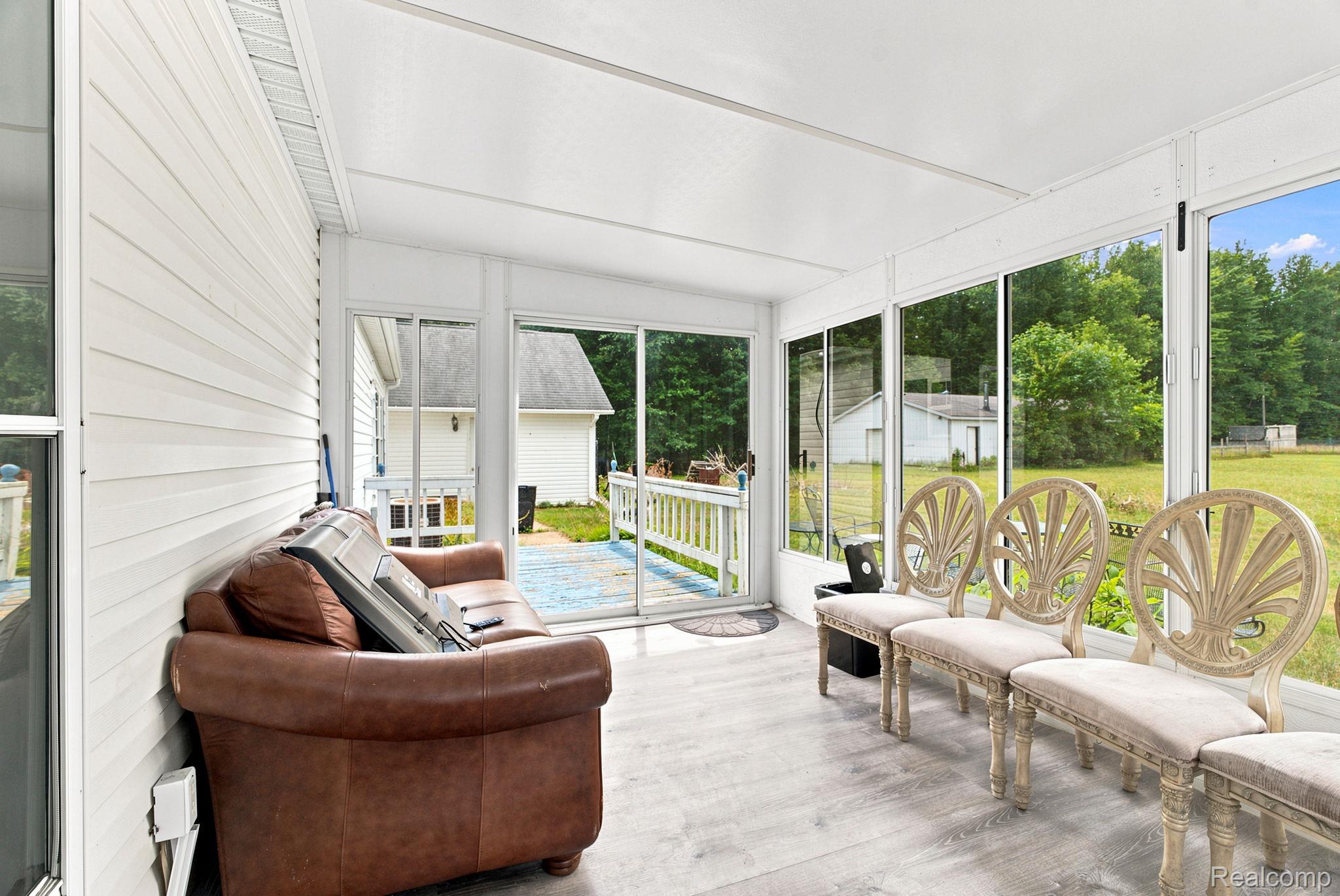 2390 Lakeshore Road Applegate, MI 48401 - Photo 19 of 97 Enclosed sunroom featuring wood-finish flooring, white paneled walls, and expansive windows