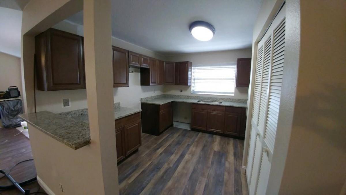 1841 Southwest Palm City Road, Unit D102 Stuart, FL 34994 - Photo 4 of 17 a kitchen with a sink a stove cabinets and a wooden floor