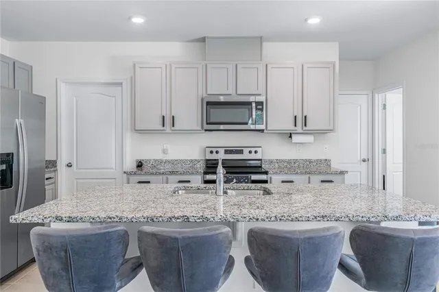 a kitchen with stainless steel appliances granite countertop a sink stove microwave and refrigerator