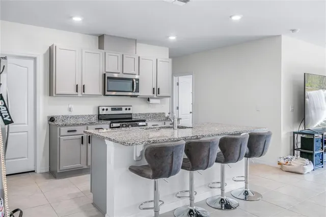 a kitchen with stainless steel appliances granite countertop a stove a sink a microwave a dining table and chairs
