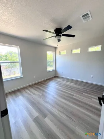an empty room with wooden floor and windows