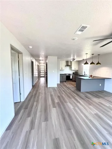 a open kitchen with stainless steel appliances granite countertop a refrigerator a sink dishwasher a stove and a dining table with wooden floor