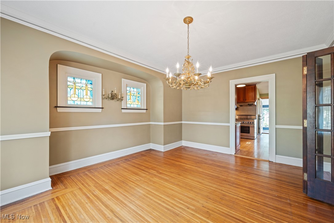 24510 Lake Road Bay Village, OH 44140 - Photo 18 of 45 Empty room featuring wood finished floors, ornamental molding, and a chandelier