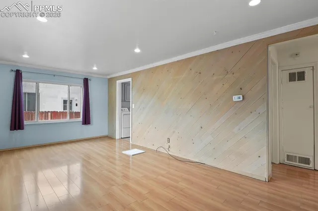 an empty room with wooden floor and windows