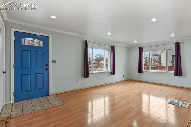 a view of an empty room with window and wooden floor