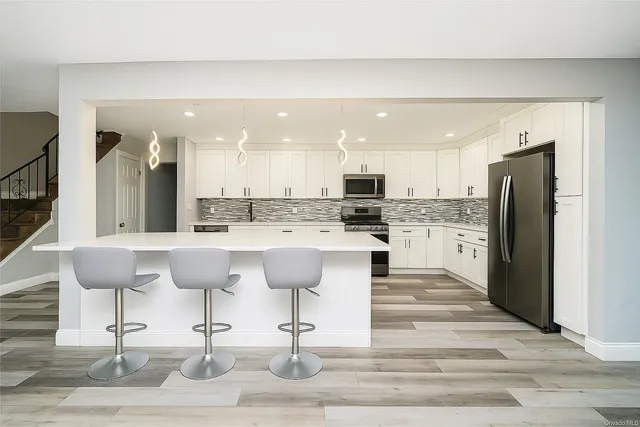 a kitchen with stainless steel appliances kitchen island granite countertop a refrigerator and a stove top oven