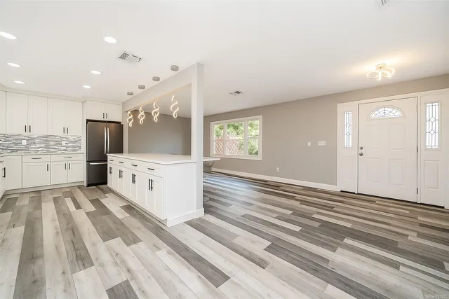 a view of a kitchen with kitchen island white cabinets appliances and a window