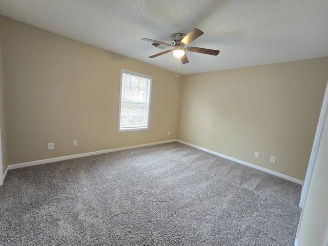 an empty room with windows and chandelier fan