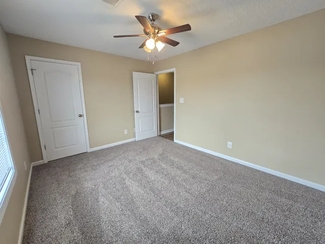 an empty room with closet and a ceiling fan