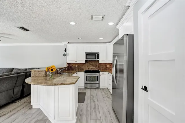 a kitchen with kitchen island granite countertop a sink a counter space appliances and cabinets
