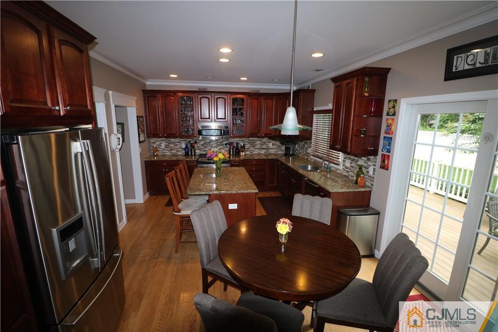 70 Willow Road Metuchen, NJ 08840 - Photo 7 of 25 a kitchen with stainless steel appliances granite countertop a refrigerator a stove a sink a dining table and chairs with wooden floor
