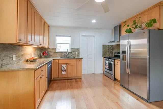 a kitchen with granite countertop a refrigerator and a stove top oven