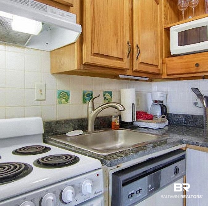 375 Plantation Road, Unit 5602 Gulf Shores, AL 36542 - Photo 10 of 11 Kitchen featuring wood cabinetry, white tile backsplash, a stainless-steel sink with a gooseneck faucet, a white electric range, and a built-in dishwasher