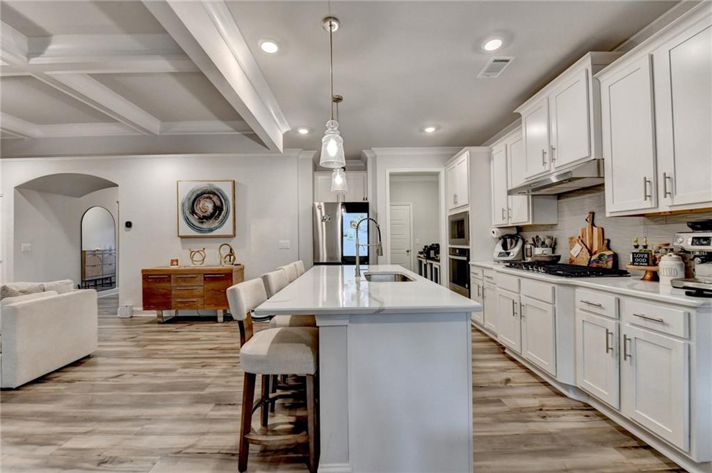 298 Ryston Way Grayson, GA 30017 - Photo 15 of 51 a kitchen with stainless steel appliances kitchen island granite countertop a stove a sink a refrigerator and white cabinets with wooden floor