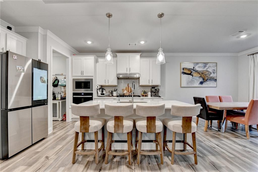 298 Ryston Way Grayson, GA 30017 - Photo 10 of 51 a kitchen with stainless steel appliances kitchen island granite countertop a dining table chairs refrigerator and sink