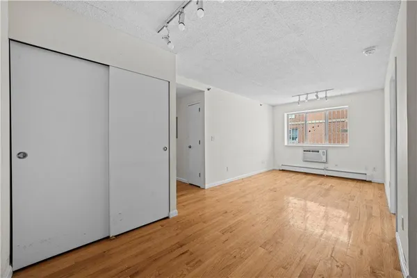 a view of an empty room with wooden floor and a window