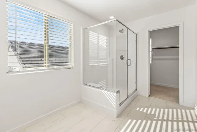 a spacious bathroom with a glass shower door and a window