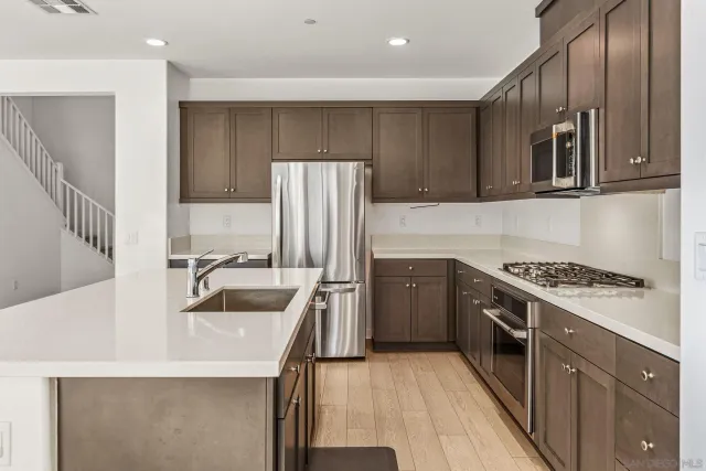 a kitchen with stainless steel appliances granite countertop a sink stove and refrigerator