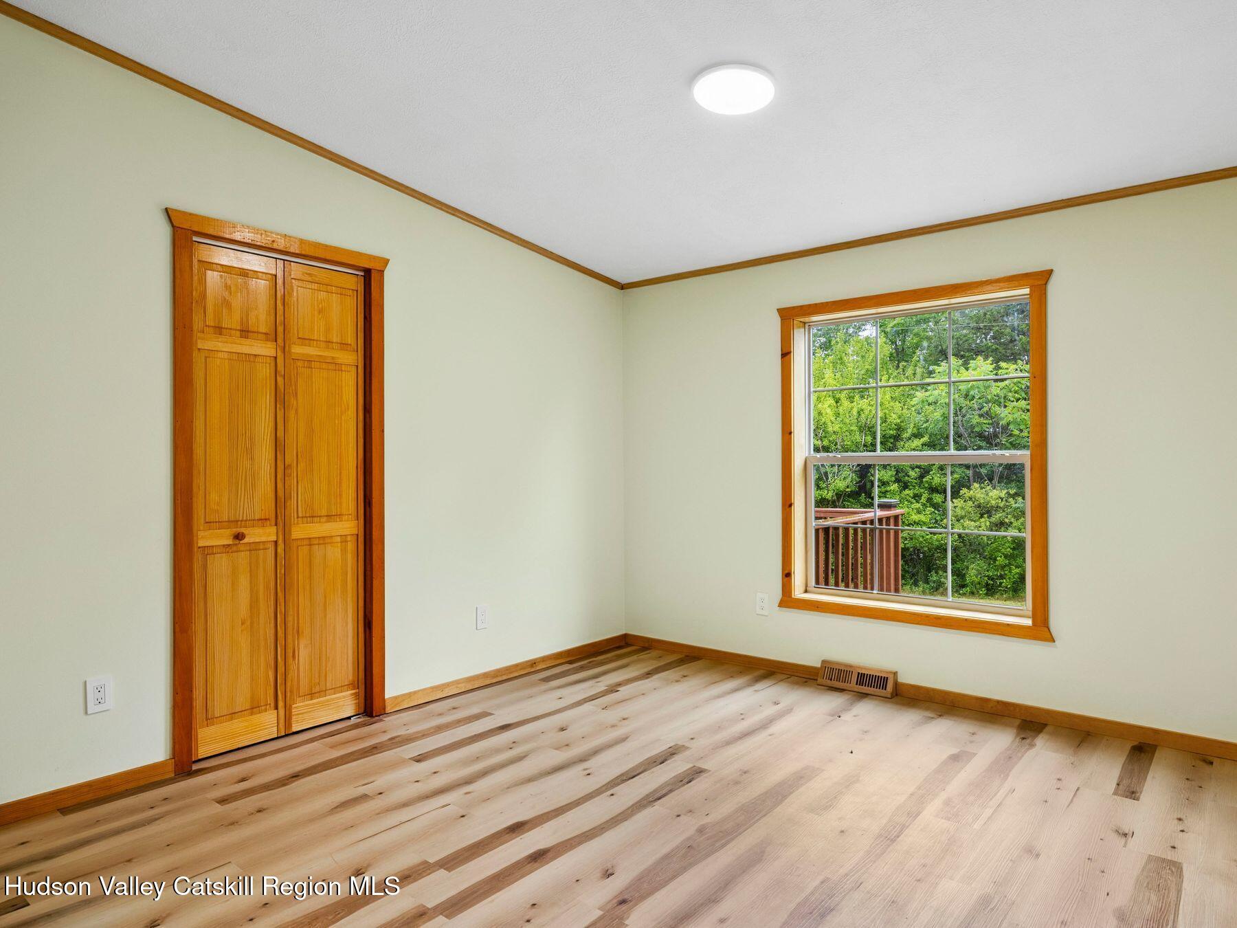 719 Allen Teator Road Durham, NY 12469 - Photo 21 of 38 a view of an empty room with wooden floor and a window