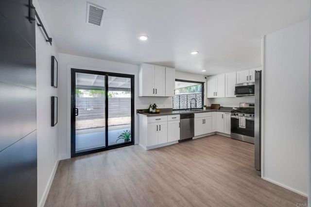 a kitchen with a white cabinets and wooden floor