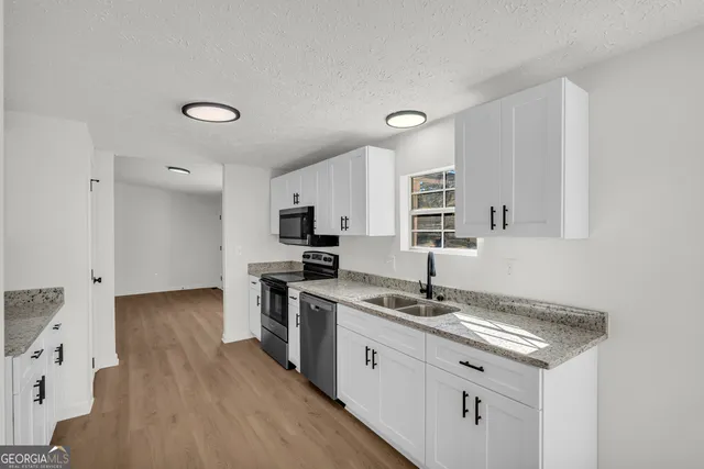 a kitchen with granite countertop a sink appliances and cabinets