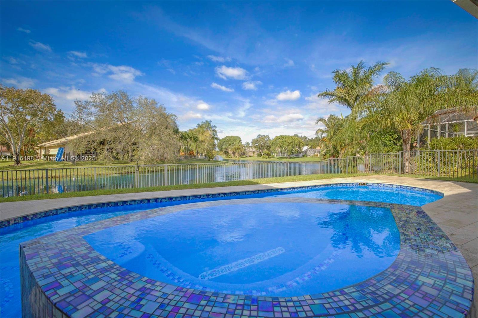 10133 Northwest 48th Drive Coral Springs, FL 33076 - Photo 42 of 49 a view of a swimming pool and lake from a bench