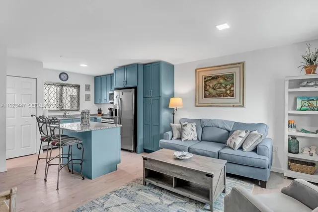 a living room with furniture a refrigerator and kitchen view