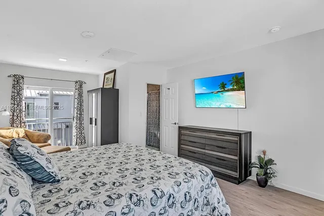 a bedroom with a bed a dresser and painting on the wall
