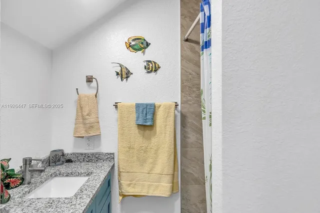 a bathroom with a granite countertop sink a mirror and shower
