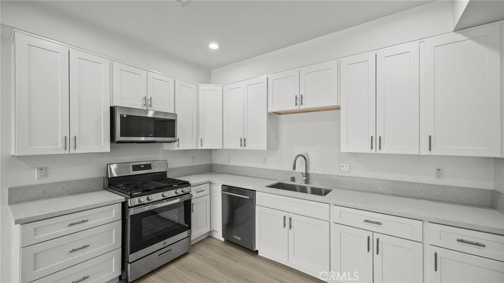 13105 Via Tuscany Riverside, CA 92503 - Photo 21 of 51 a kitchen with white cabinets and stainless steel appliances