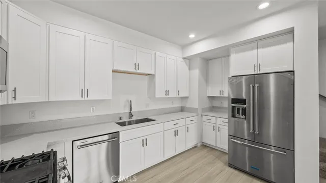 a kitchen with a refrigerator sink and cabinets
