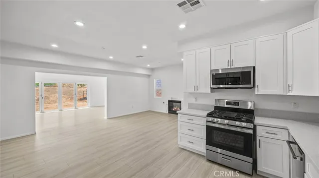 a kitchen with stainless steel appliances a stove a microwave and white cabinets