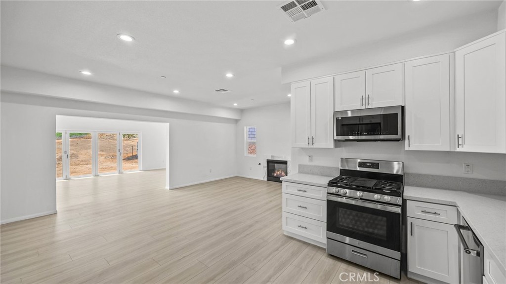 13105 Via Tuscany Riverside, CA 92503 - Photo 24 of 51 a kitchen with stainless steel appliances a stove a microwave and white cabinets