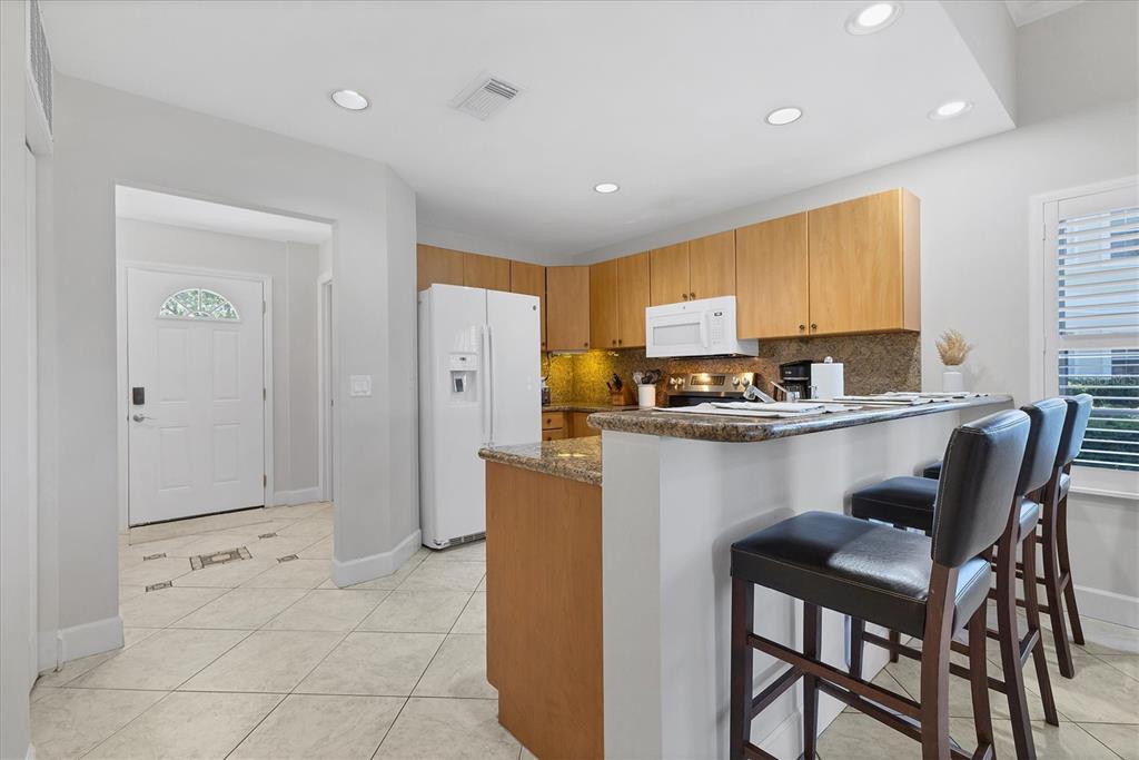 3605 54th Drive West, Unit 104 Bradenton, FL 34210 - Photo 12 of 65 a kitchen with stainless steel appliances granite countertop a refrigerator a stove a sink a dining table and chairs with white cabinets