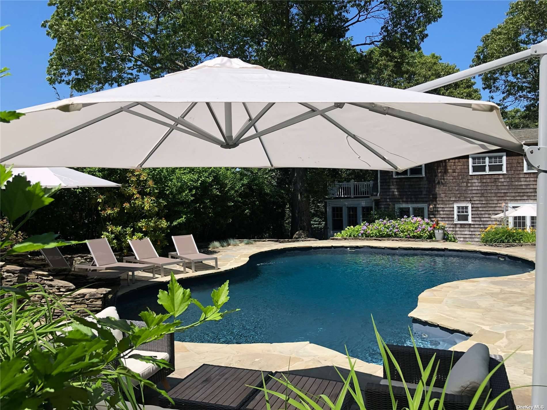 3752 Noyack Road Sag Harbor, NY 11963 - Photo 19 of 28 a view of a patio with table and chairs under an umbrella