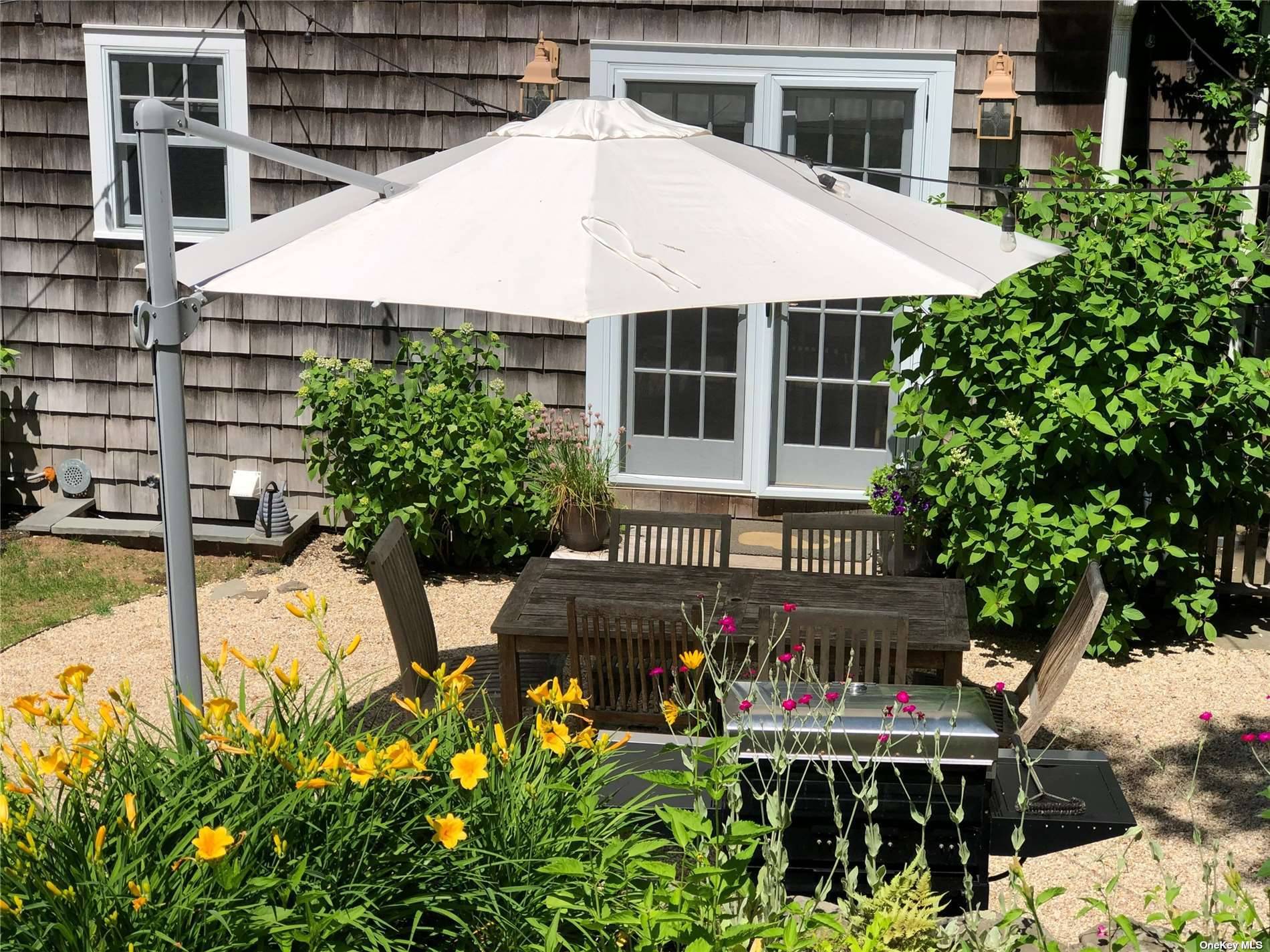 3752 Noyack Road Sag Harbor, NY 11963 - Photo 26 of 28 a view of a patio with table and chairs and potted plants