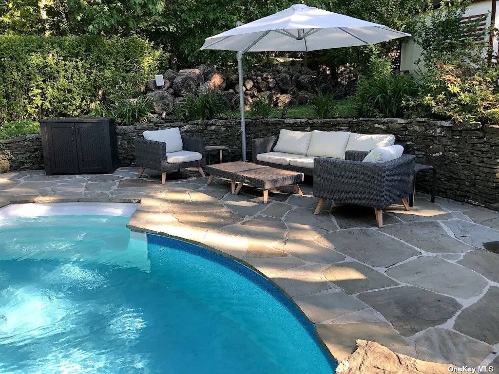 3752 Noyack Road Sag Harbor, NY 11963 - Photo 27 of 28 a view of a patio with a table and chairs under an umbrella
