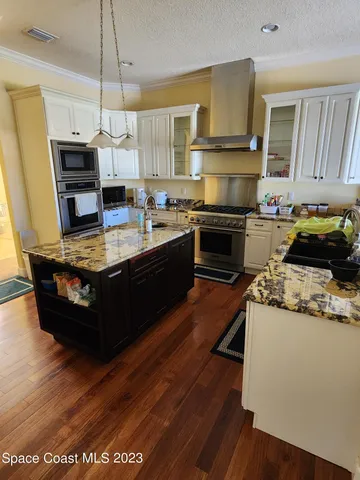 a kitchen with kitchen island granite countertop a sink cabinets and stainless steel appliances