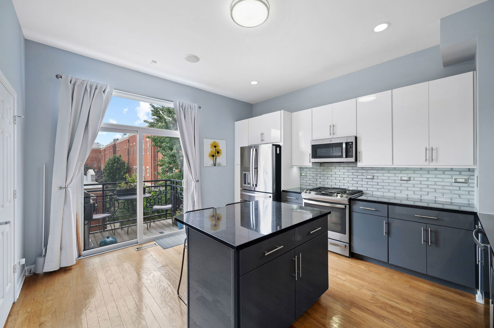 813 West University Lane Chicago, IL 60608 - Photo 15 of 33 a kitchen with stainless steel appliances granite countertop a stove top oven a sink dishwasher a refrigerator and a dining table with wooden floor