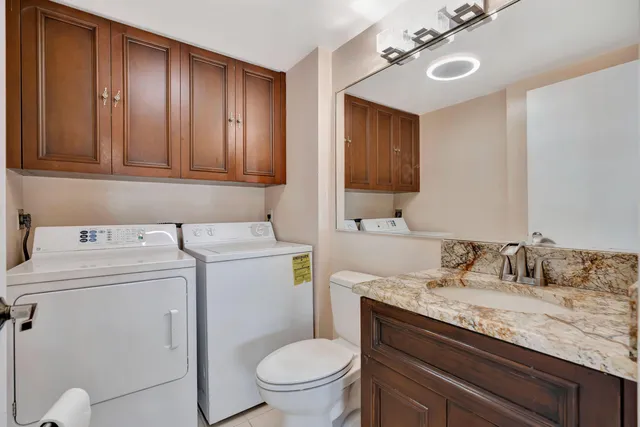 a bathroom with a granite countertop sink and a toilet
