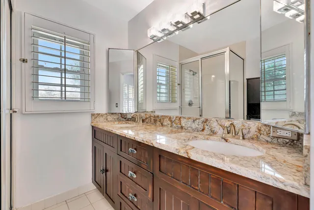 a bathroom with a granite countertop double vanity sink and a mirror