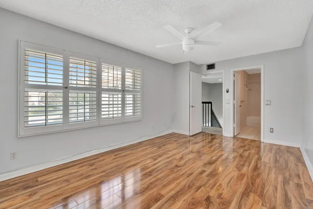 a view of empty room with wooden floor and fan