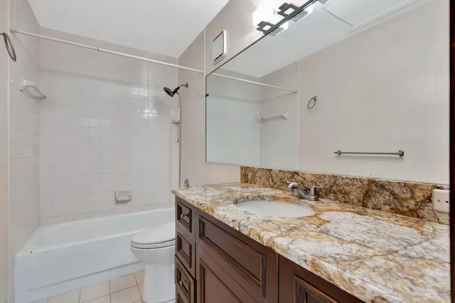 a bathroom with a granite countertop sink a toilet and shower
