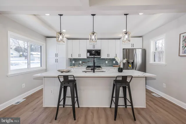 a kitchen with stainless steel appliances kitchen island a dining table chairs and wooden floor