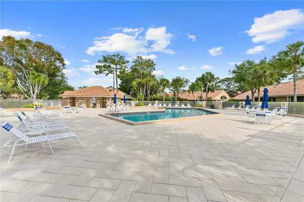 a view of swimming pool with outdoor seating and trees in the background