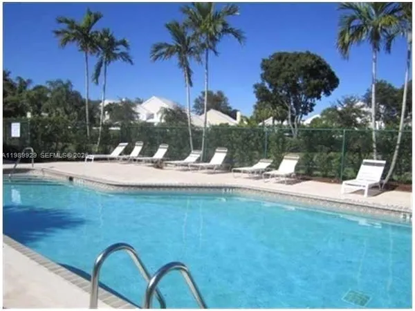 a view of swimming pool with a yard and palm trees