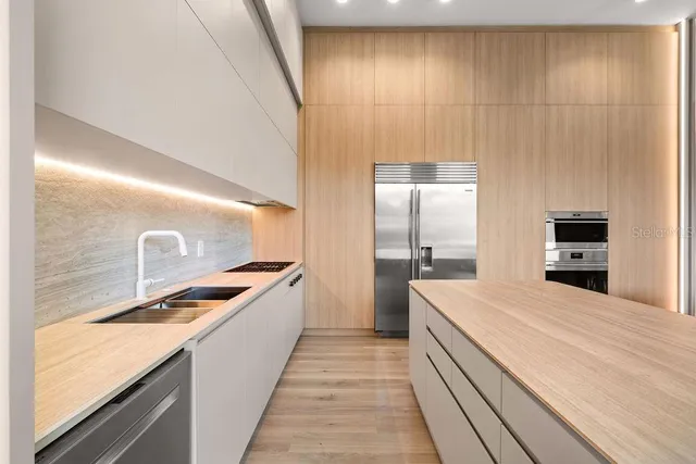 a large white kitchen with granite countertop a sink and dishwasher a stove top oven with wooden floor